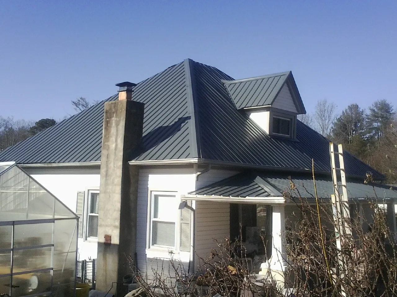 Dark blue standing seam metal roof on a white farmhouse with dormer — Slate & Tile Roof Repair by Roofing Brothers in Hartford City