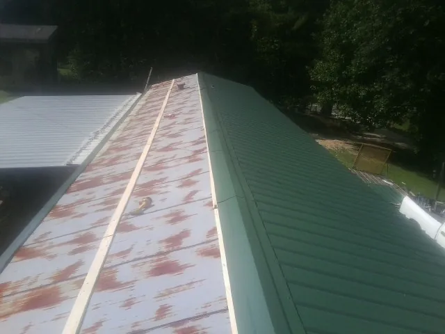 Old rusted panels beside newly installed green metal roofing — Wind Damage Roof Repair by Roofing Brothers in Hartford City