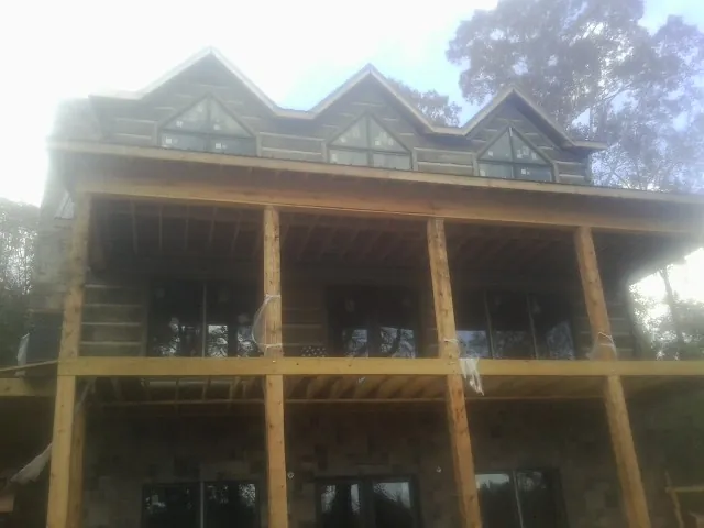 Dormers and porch framing on a large log home under construction — Roof Coating work by our crew in Hartford City