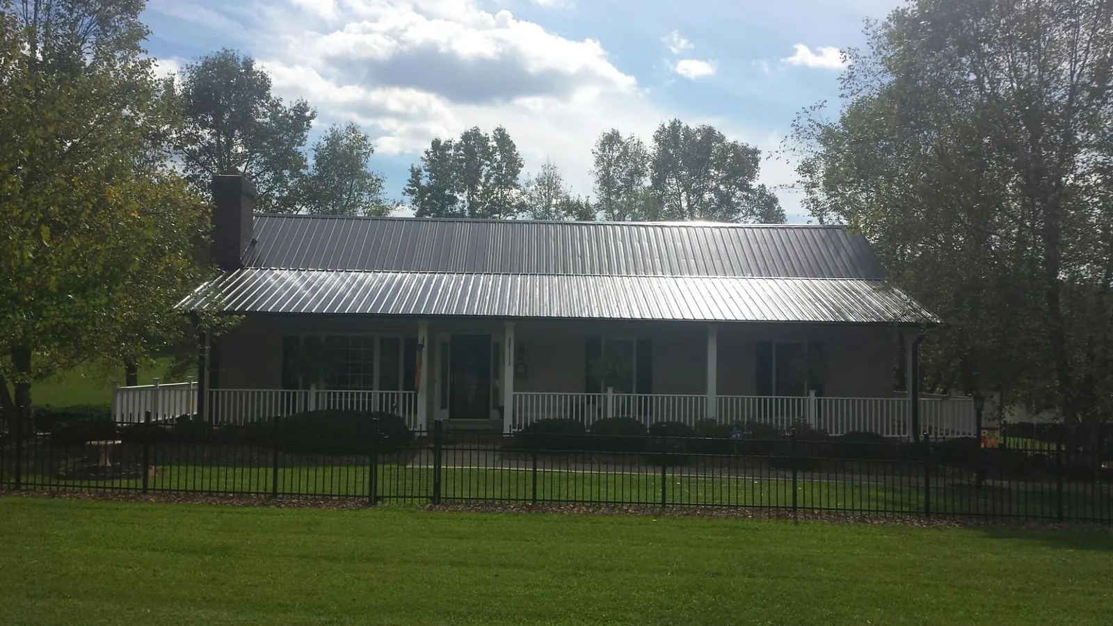 Gray metal roof on a brick ranch with a full width front porch — Gutter Guard Installation work by our crew in Hartford City