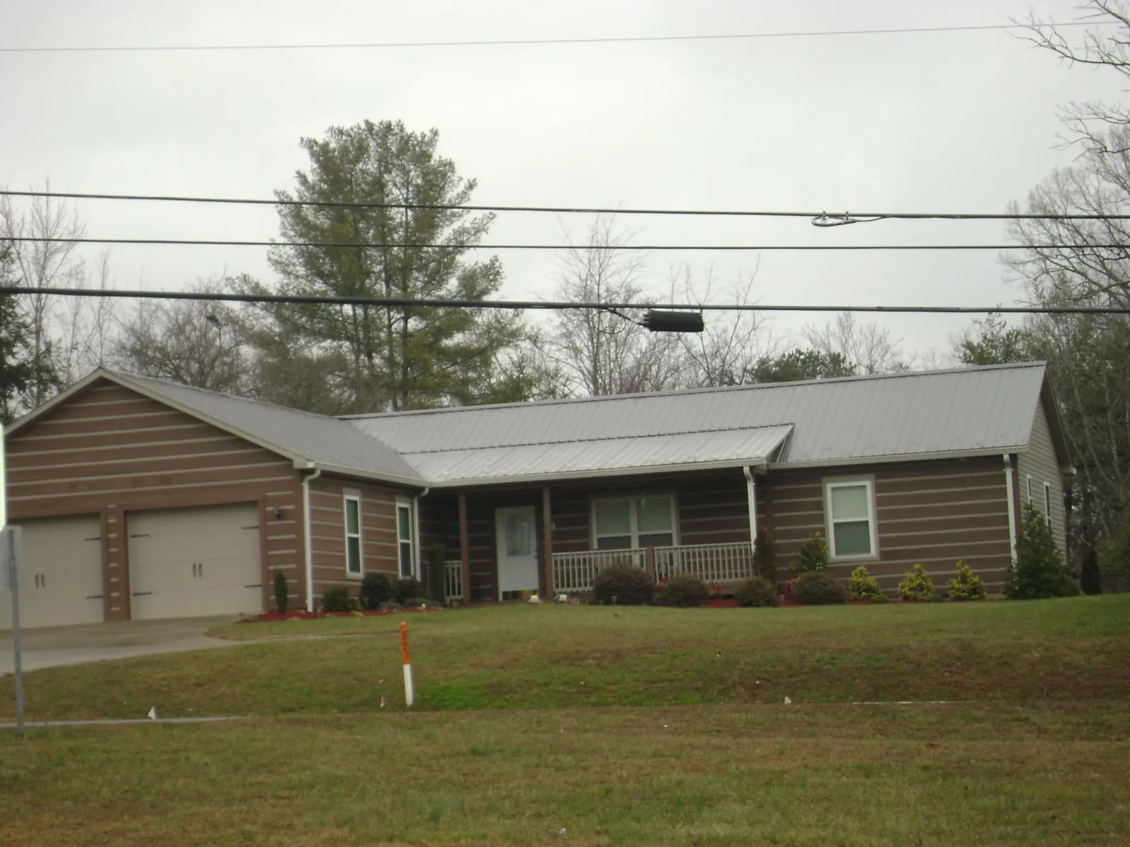 Gray metal roof on a log sided ranch home with a front porch in Hartford City