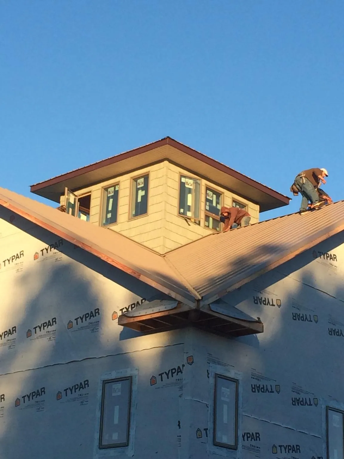 Roofers working around a rooftop cupola on a new metal roof at sunset — Roof Waterproofing in Hartford City by Roofing Brothers